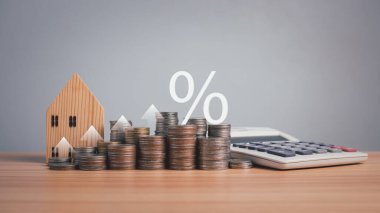 Manken ahşap ev, hesap makinesi ve paralar tahta zemine dizilmiş beyaz arka plan. Mortgage, loand, transfer, finans, tasarruf ve yatırım kavramları. Emlak vergisi kavramları.