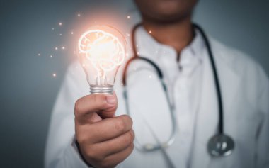 Doktor, gri arka planda beyin simgesi olan ampulü tutuyor. Sağlık hizmetleri ve sağlık hizmetleri. Tıbbi servis teknolojisi..