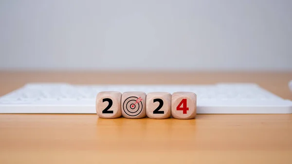 Wooden blocks line the wooden floor and bear the letters 2024, representing the setting of goals for 2024, the idea of a startup. Financial planning, development, business strategy Setting business goals