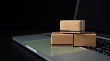 Karanlık arka planda dizüstü bilgisayarda kutular. Çevrimiçi alışveriş, çevrimiçi alışveriş fikri tüketicilerin internet üzerinden doğrudan mal satın almalarına olanak sağlayan bir elektronik ticaret biçimidir..