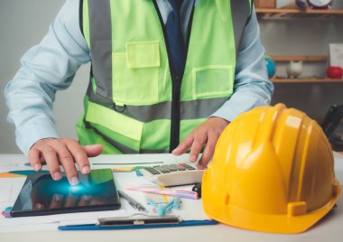 Tablet üzerinde çalışmak için tablet kullanan mimar veya mühendis, maliyet hesaplaması, inşaat planlaması, yapısal hesaplama, inşaat maliyeti planlaması, yapısal tasarım, proje sunum planı.