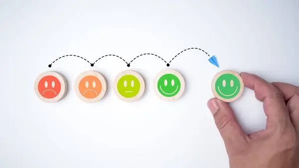 stock image Customer service concept, Global best business scoring experience satisfaction survey concept, Human hand selects a smiley face on a wooden block, Mental health positive thinking.