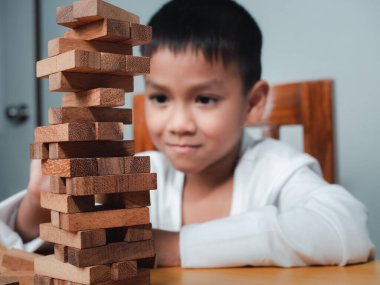 Neşeli Asyalı çocuk ahşap yapı taşlarıyla oynuyor Jenga 'da eğleniyor ve yaratıcılık öğreniyor, zeki çocuk konsepti, tahta blok planlaması, risk ve iş dünyasındaki proje yönetimi stratejisi..