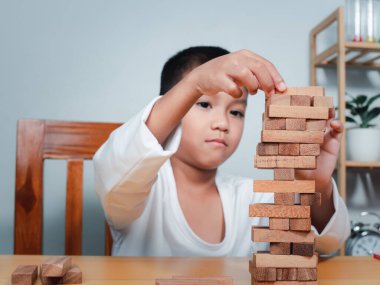 Neşeli Asyalı çocuk ahşap yapı taşlarıyla oynuyor Jenga 'da eğleniyor ve yaratıcılık öğreniyor, zeki çocuk konsepti, tahta blok planlaması, risk ve iş dünyasındaki proje yönetimi stratejisi..