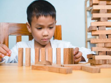 Neşeli Asyalı çocuk ahşap yapı taşlarıyla oynuyor Jenga 'da eğleniyor ve yaratıcılık öğreniyor, zeki çocuk konsepti, tahta blok planlaması, risk ve iş dünyasındaki proje yönetimi stratejisi..