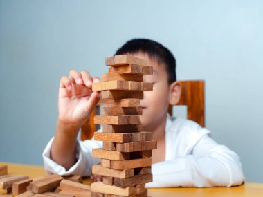 Neşeli Asyalı çocuk ahşap yapı taşlarıyla oynuyor Jenga 'da eğleniyor ve yaratıcılık öğreniyor, zeki çocuk konsepti, tahta blok planlaması, risk ve iş dünyasındaki proje yönetimi stratejisi..