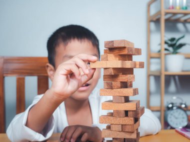 Neşeli Asyalı çocuk ahşap yapı taşlarıyla oynuyor Jenga 'da eğleniyor ve yaratıcılık öğreniyor, zeki çocuk konsepti, tahta blok planlaması, risk ve iş dünyasındaki proje yönetimi stratejisi..