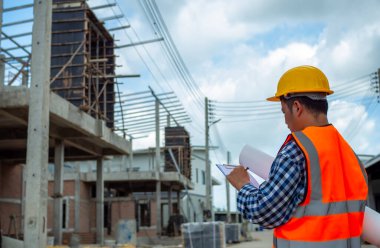 Projeyi elinde tutan mühendisler açık havada bir inşaat alanı, mühendislik ve mimari konsepti üzerine planları olan büyük bir inşaat projesinin şantiyesinde çalışan mühendis..