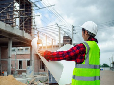 Projeyi elinde tutan mühendisler açık havada bir inşaat alanı, mühendislik ve mimari konsepti üzerine planları olan büyük bir inşaat projesinin şantiyesinde çalışan mühendis..