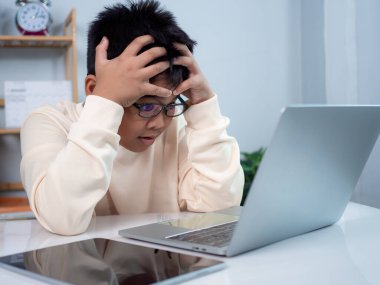 Bilgisayarı öğrenmek için kullanan ve çevrimiçi öğrenme, uzaktan eğitim, evde eğitim ve çevrimiçi eğitim konsepti ile okul öğretmeninden sanal internet dersi hakkında vurgulayan çocuk.