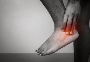 Gri arka planda bacağı ağrıyan kadın ayak bileği, ayak bileği ve bacak tedavisi, bilek kası spazmı, sağlık ve sağlık sigortası, yaralanma ve tıbbi konsept ile kadın masajı..