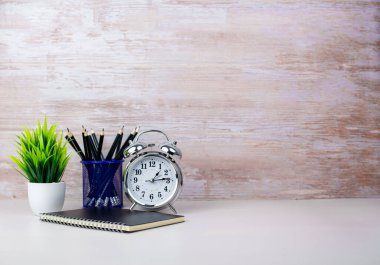 Çalışma alanı beyaz masa üstünü klasik defter, kalem ve yeşil çiçekle kaplıyor. Ürün görüntüleme kurgusu için uzay masasını kopyala. Tedarikli minimalist beyaz iş yeri.