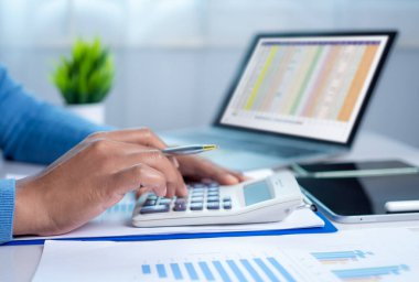 İş kadını el yazısı, maliyet, hesap makinesi ve bilgisayarla ilgili finansman ile sabah ışığında masada tablet, iş muhasebe konsepti, bakiye hesaplama veya denetleme gibi konularda çalışıyor..
