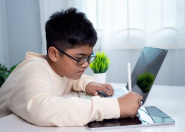Asyalı öğrenci bilgisayar ve tablet öğreniyor. Teknoloji konsepti eğitimi, evde kalmak, modern eğitici bir yaşam tarzı sunmak. Okul öğretmeninden sanal internet kursu.