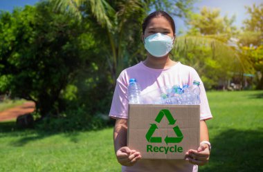 Çöp toplayan ve elinde plastik şişelerle geri dönüşüm kutusunu tutan kadın, geri dönüşüm konsepti, plastiksiz yiyecek plastik ambalajı, çevre kirliliğinin azaltılması.