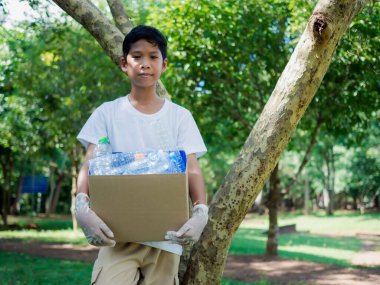 Çevre kirliliğinin azaltılması ve geri dönüşüm konsepti, Plastiksiz, hurda gıda plastik ambalajı. Çocuk geri dönüşüm için karton kutular tutuyor ve dışarıda plastik şişelerle birlikte bir geri dönüşüm kutusu tutuyor..