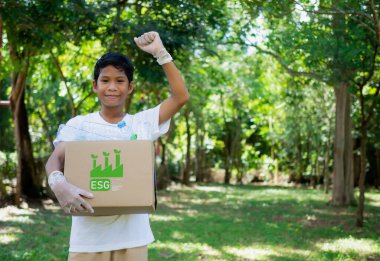 Çevre kirliliğinin azaltılması ve geri dönüşüm konsepti, Plastiksiz, hurda gıda plastik ambalajı. Çocuk geri dönüşüm için karton kutular tutuyor ve dışarıda plastik şişelerle birlikte bir geri dönüşüm kutusu tutuyor..