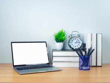 Metnini kopyalamak için boşluk. Beyaz masadaki boş ekranlı dizüstü bilgisayar ve ahşap arka planda ofis malzemeleri. Çalışma alanı ve kopyalama alanı. Ofis malzemeleriyle dolu masa..