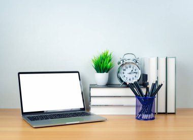 Beyaz masadaki boş ekranlı dizüstü bilgisayar ve ahşap arka planda ofis malzemeleri. Metnini kopyalamak için boşluk. Çalışma alanı ve kopyalama alanı. Ofis malzemeleriyle dolu masa..