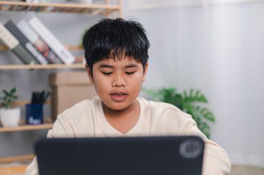 Asyalı öğrenci tablet öğrenme, teknoloji eğitimi, evde kalma, modern eğitim yaşam biçimi sunma, okul öğretmeninden sanal internet dersi.