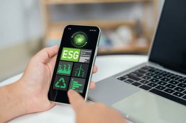 İş Yatırım Stratejisi, Çevre Sosyal Yönetimi Yatırım İş Konsepti, Çevre ve İş Büyümesi konularında ESG 'yi akıllı telefon ekranında analiz etmek için dizüstü bilgisayar kullanmak.
