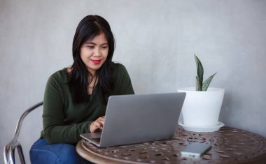 İş kadını evde dizüstü bilgisayar kullanarak çalışıyor, iş kadını klavye kullanıyor, dizüstü bilgisayar kullanıyor, gülümsüyor, ev gevşeme masasına gülüyor..