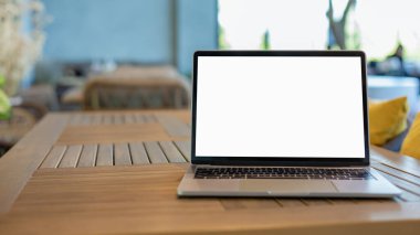 Çalışma alanı arkaplan projesi dizüstü bilgisayarda reklam mesajınız için boş bir kopya alanı ekranıyla. Boş ekranlı bir dizüstü bilgisayar ve bir kahve dükkanının içindeki ahşap bir masaya yerleştirilmiş.. 