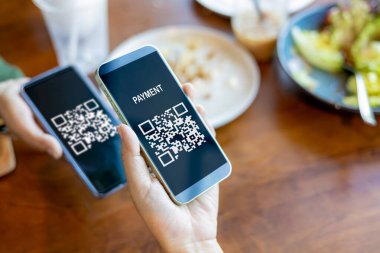 El bilgisayarı tutmak, cep telefonu uygulamasını QR kodunu taramak için kullanmak, QR kod ödemesi ya da nakitsiz teknoloji konsepti, kahve dükkanının parasız dijital ödemeyi kabul etmesi, anlamsız QR kodu.. 