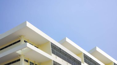 Mavi gökyüzü arka planında açık sarı bina, mavi gökyüzüne karşı modern açık sarı beton bina duvarları, gayrimenkul arazisinin bir kısmı, kopyalama alanı..