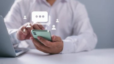 Akıllı telefon yazma, canlı sohbet ve sosyal ağ kavramları, sosyal medya pazarlama teknolojisi konsepti, evde çalışan sohbet kutuları simgeleri kullanarak iş adamı eli.