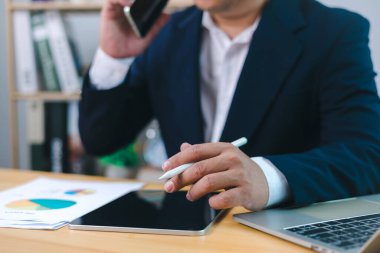 İş adamı cep telefonuyla arama yapar ve ofiste dizüstü bilgisayar kullanır, profesyonel yönetici iş yerinde telefonla konuşur, proje için tartışmayı arar, çalışanı ya da telefonu olan danışmanı arar..