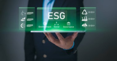 Koyu takım elbiseli bir iş adamı beyaz ekranlı bir akıllı telefon sunar.