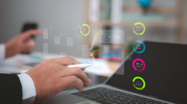 Bir dizüstü bilgisayarın üstündeki holografik veri görselleştirmeleri, grafikleri ve ölçümleri analiz eden bir iş adamı. İş zekası, finansal analiz, dijital rapor. Finans ve teknoloji kavramları..