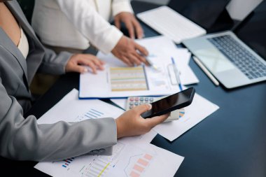 Modern ofisteki akıllı telefon, hesap makinesi ve dizüstü bilgisayar kullanarak finansal veri ve grafikleri analiz eden iş kadınlarının yakın çekimleri. Takım çalışması, finans planlaması, teknoloji ve iş birliği kavramı.