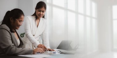 Modern bir ofiste finansal belgeleri tartışan iki profesyonel Asyalı iş kadını. Şirket iş ortamında takım çalışması, liderlik ve işbirliği kavramı.