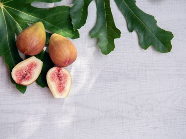 Ripe fresh fig with green leaves isolated on white wooden background.Copy space