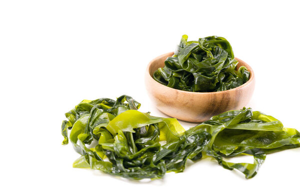 Fresh seaweed wakame in woodle bowl isolated on white background. Copy space. Japanese food