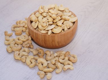 Tahta kasede kaju fıstığı, beyaz masada güneş ışığıyla. Sağlıklı yemek..