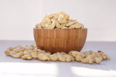 Tahta kasede kaju fıstığı, beyaz masada güneş ışığıyla. Sağlıklı yemek..