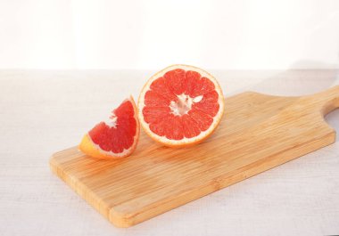 kesme tahtası üzerinde greyfurt dilimlenmiş.