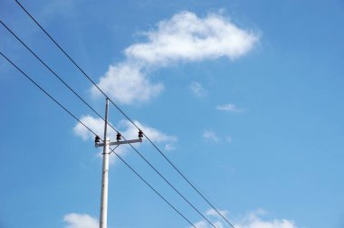 Elektrik direğinin elektrik kabloları bulutlu mavi gökyüzünde elektrik kablolarına karşı.                                                                        