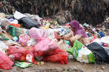 Sangatta, Doğu Kalimantan, Endonezya - 03 Ağustos 2020: Bir kadın çöp sahasında satmak için plastik topluyor                                                             
