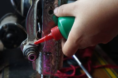 El ele tutuşan dikiş makinesi yağı şişesi. Dikiş makinesinin yağlama parçaları                                                              
