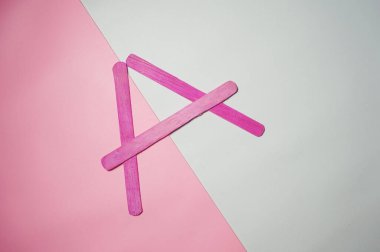 Pembe ve beyaz arka planda izole edilmiş ahşap dondurma çubuğundan bir sembol. Seçici Odaklanma                                   