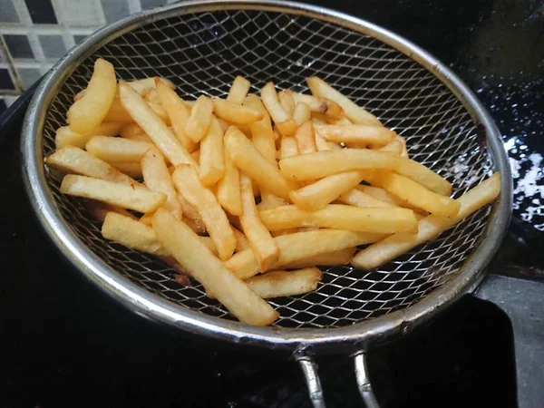 둥지에서 요리용 기름에서 감자튀김을 짜내는 — 스톡 사진