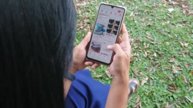 Çekim editörü, Endonezya, 30 Ekim 2022, akıllı telefonunda sosyal medyayı karıştıran kadın.
