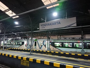 fotoğraf editörü, yogyakarta, yogya, jogja, jogjakarta, endonezya, merkez java, büyük asılı beyaz saat ve tren istasyonu işareti arasında hareket, bazı yolcular görüldü