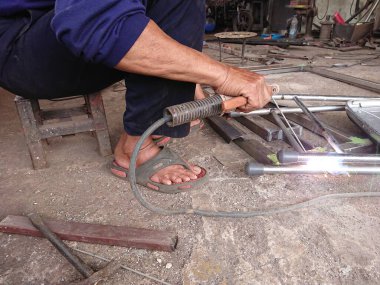 close up, man welding broken chair at his workshop