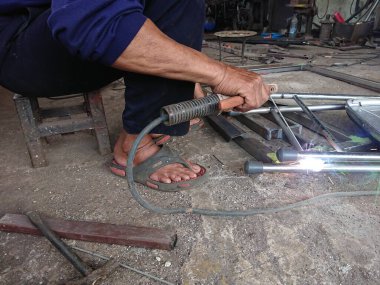 close up, man welding broken chair at his workshop