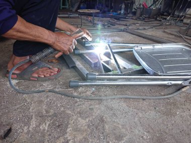 close up, man welding broken chair at his workshop